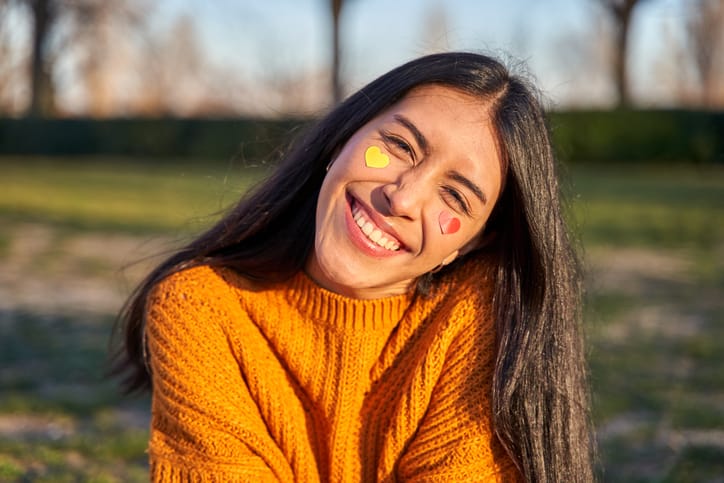 single woman in orange sweater smiling