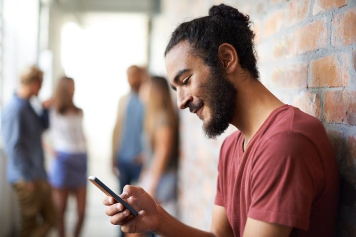 guy texting against brick wall