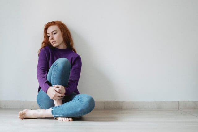 sad redhead sitting against wall