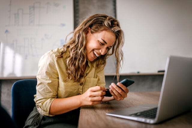 woman smiling while texting