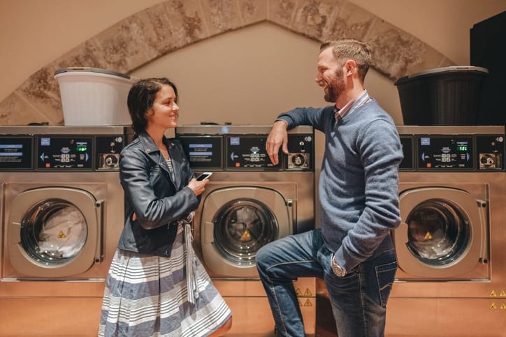 Young couple chatting at a laundromat.