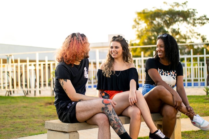 Three friends in a group laughing outdoors.