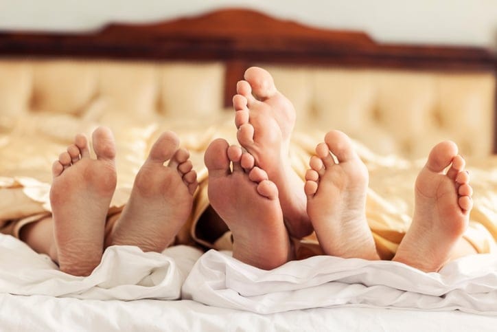Pairs of feet in bed.