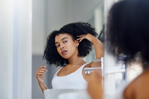 Young woman styling her hair in her bathroom.