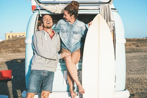 Happy surfers standing on vintage camper.