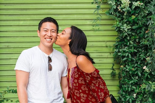 Woman kissing her boyfriend's cheek.