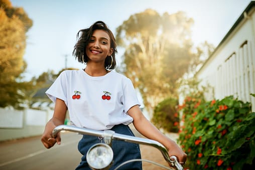 Young woman standing and posing with her bicycle.