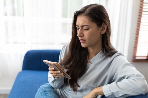 Woman reads bad news on mobile phone.