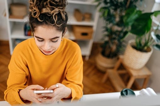 Businesswoman using smart phone at desk in office.