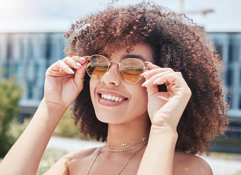 Young woman smiling alone outside.
