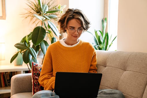 smiling woman working on laptop in living room