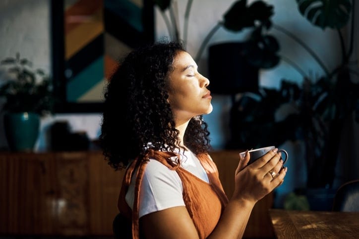 woman meditating closed eyes coffee window