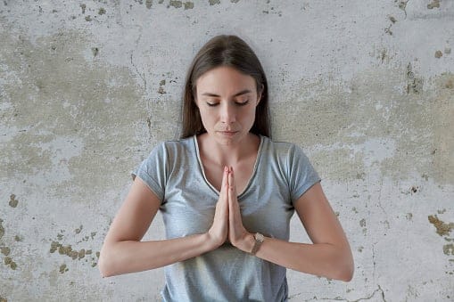 Young female holding hands in namaste or prayer.