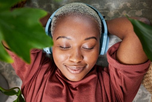 A woman with her eyes closed listening to mindfully listening to music or a meditation track.