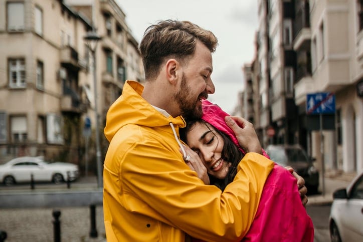 smiling couple embracing in rainy city