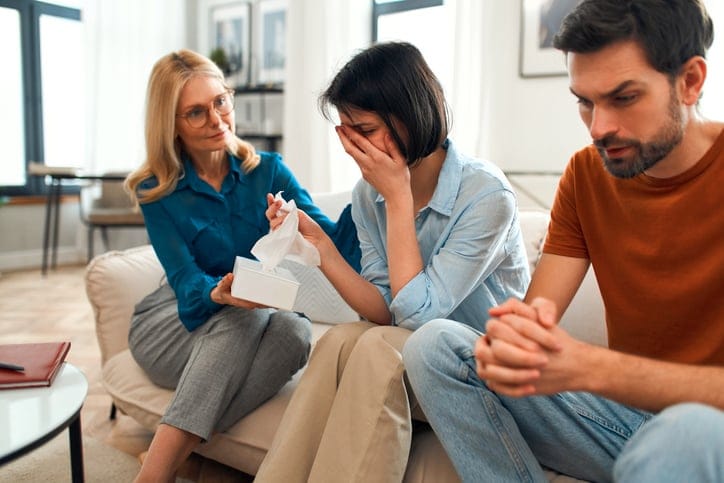 Family comforting an upset woman.