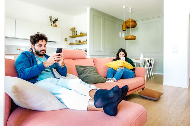 couple ignoring each other on phones in living room