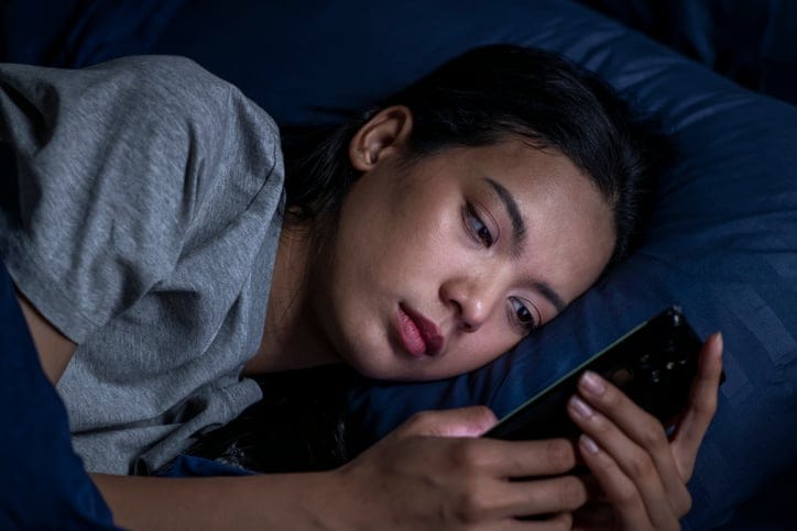 Serious woman texting in bed at night.