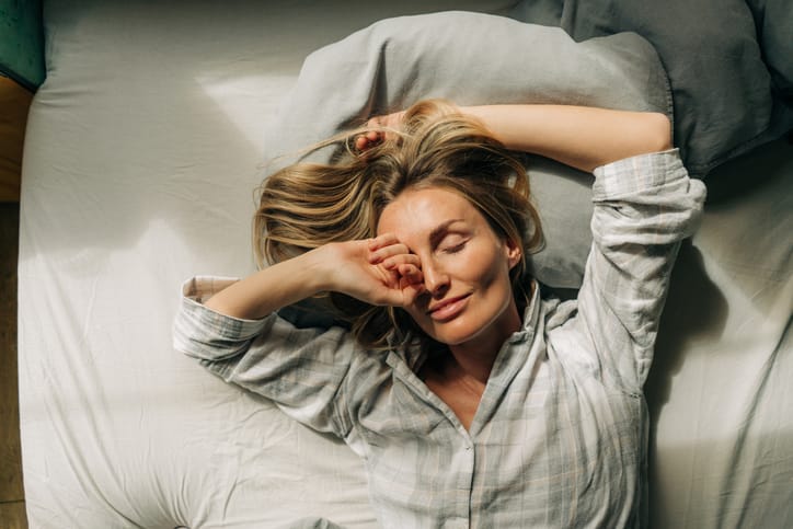 Woman lies in bed after waking up.