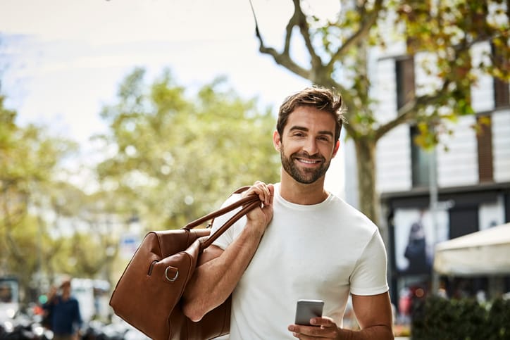 Businessman carrying his bag and holding smart phone.