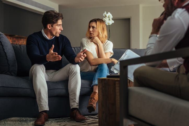 Couple arguing during therapy session with psychologist.