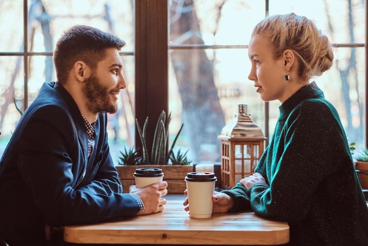 omantic couple in the cafe is drinking coffee and talking. Handsome man and beautiful girl enjoying being together.