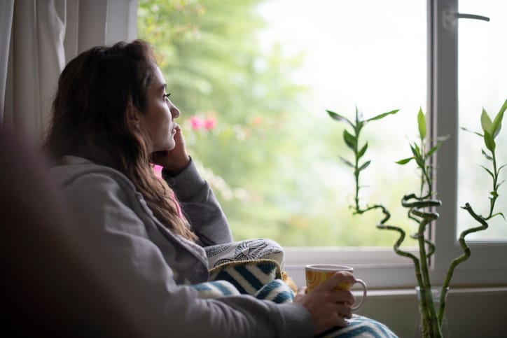 depressed woman sitting by window