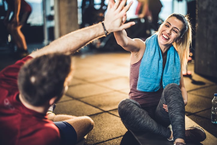 Female athlete giving her boyfriend a high-five on a break in a gym.