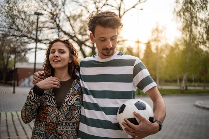 Couple playing soccer at sunset.