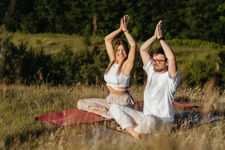 Couple meditating in a field.
