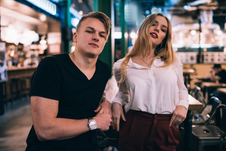 Young man and woman standing near table in cafe