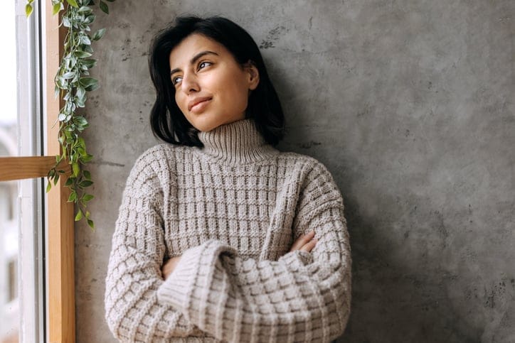 Portrait of young beautiful woman contemplating her thoughts while looking through window