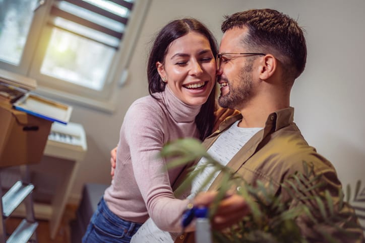 Smiling couple unpacking boxes in new home.