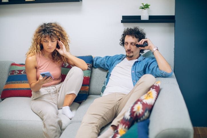 annoyed couple sitting on couch