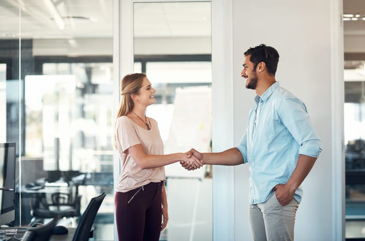 man and woman shaking hands in office