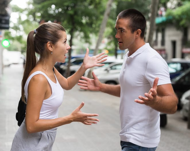 Angry man and woman quarreling on street.
