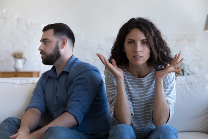 Annoyed married couple sitting on couch.