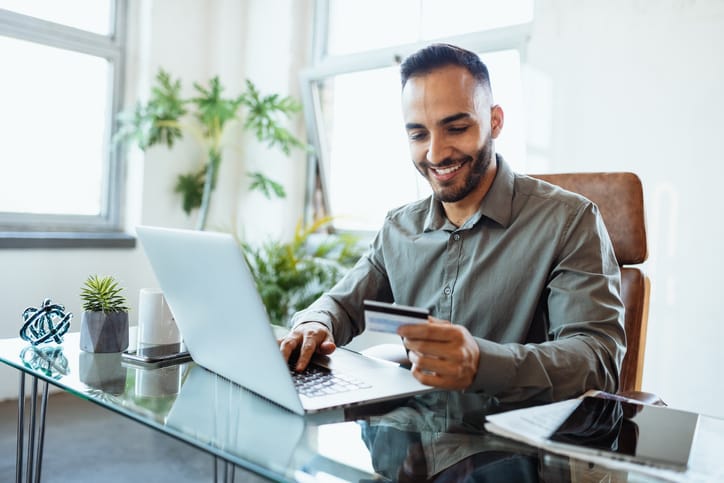 Businessman in office, using credit card to pay online.