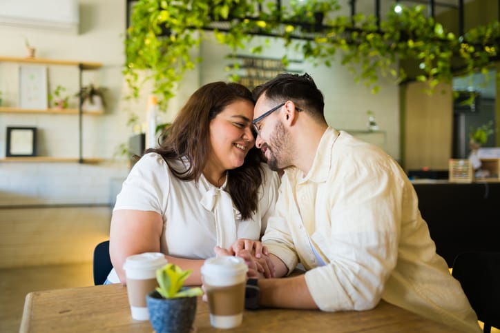 Smiling couple in love holding hands during a date at a cafe and having a romantic moment