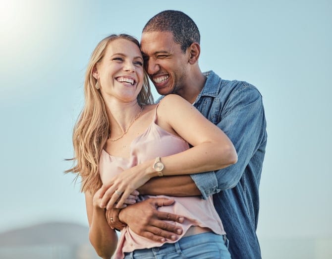 Happy man and woman hugging together outdoors.