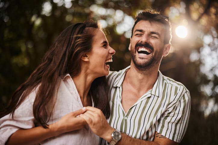 Cheerful couple having fun while holding hands in summer day in nature.