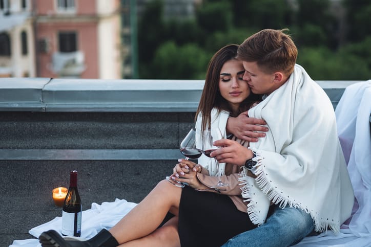 woman being cuddled by man on rooftop