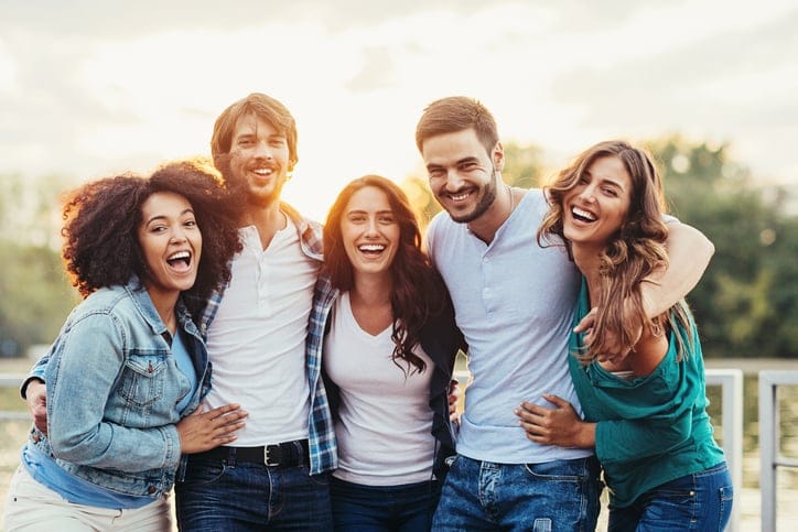 Multi-ethnic group of five young pople holding together outdoors at sunlight