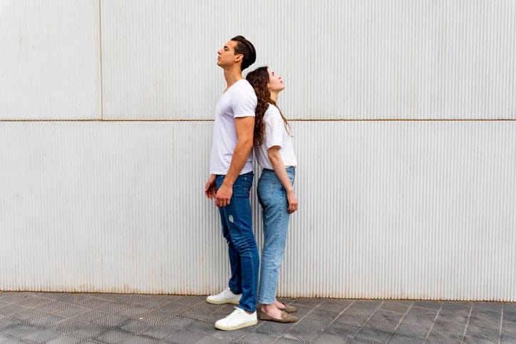 couple standing back to back outside