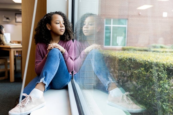 lonely pre-teen girl looking out window