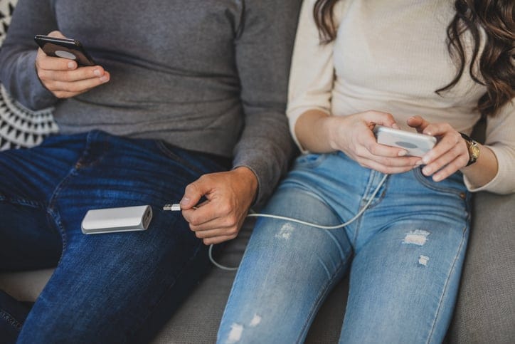 Couple charging smart phones with power bank