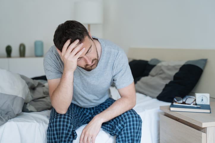 Restless man waking up early with headache.