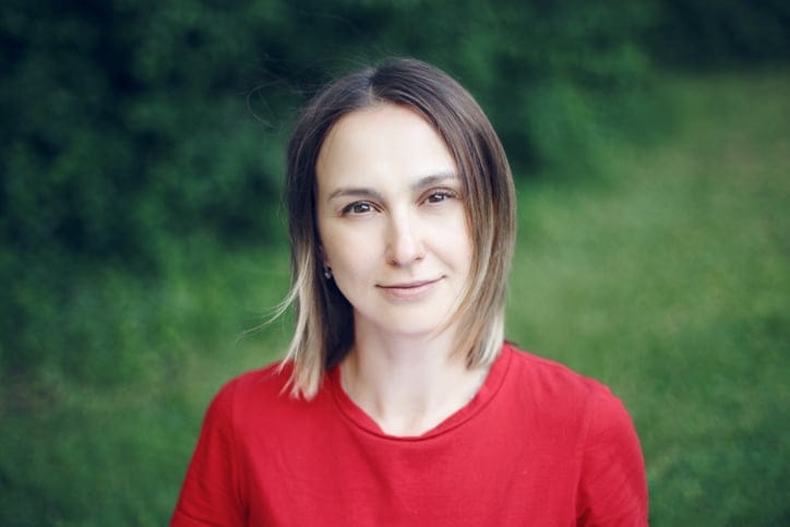 Portrait head shot of beautiful pensive Caucasian middle age woman with long light bob hair. Casual style real person in red t-shirt.
