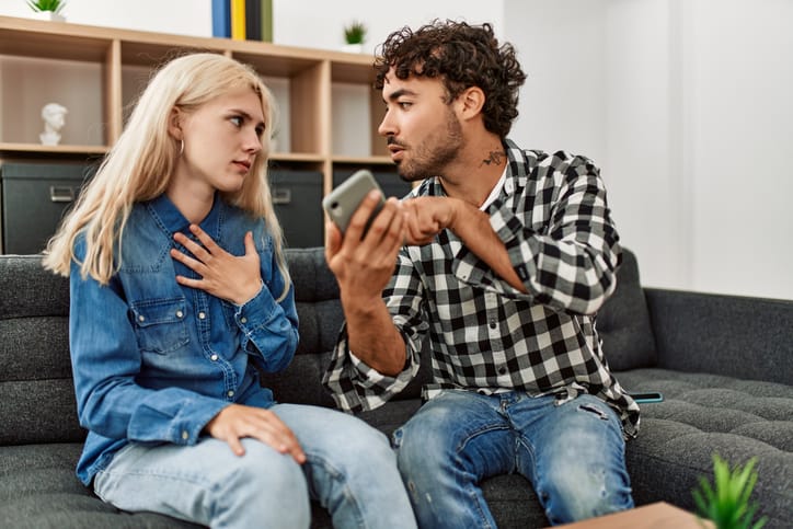 Young couple sitting on the sofa discussing at home.