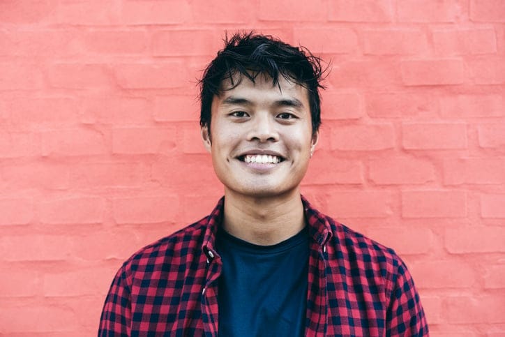 smiling young man in front of pink wall